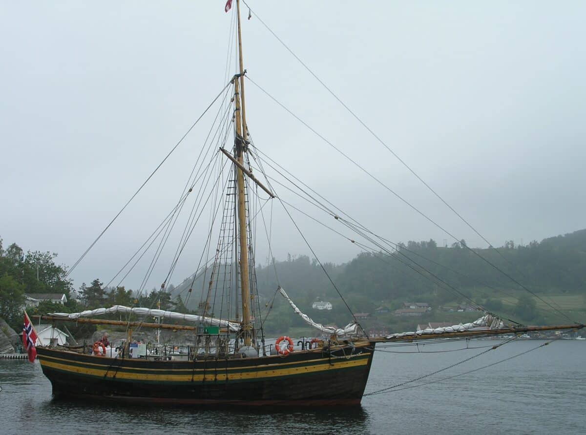 The replica of the sloop Restauration visiting Ramsvig old Trading Post for seafarers in the calm waters of the Sjernarøyene islands.