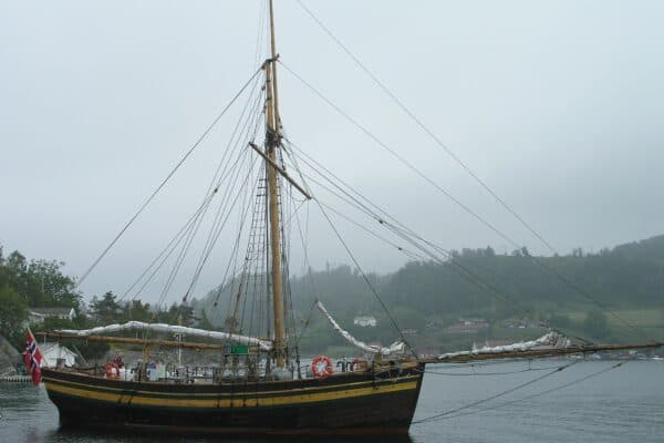 The replica of the sloop Restauration visiting Ramsvig old Trading Post for seafarers in the calm waters of the Sjernarøyene islands.
